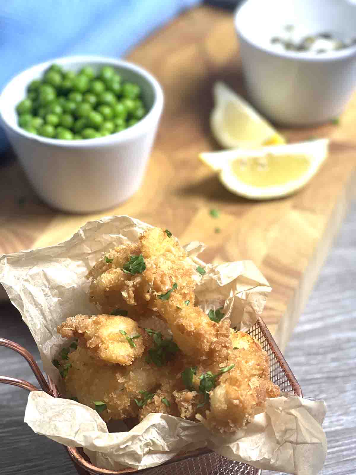 cod fish bites in a pot with tartare sauce in the background.
