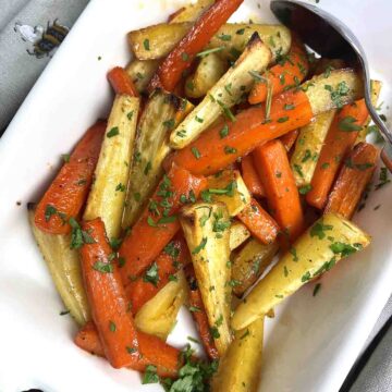honey roasted carrots and parsnips in a white serving dish.