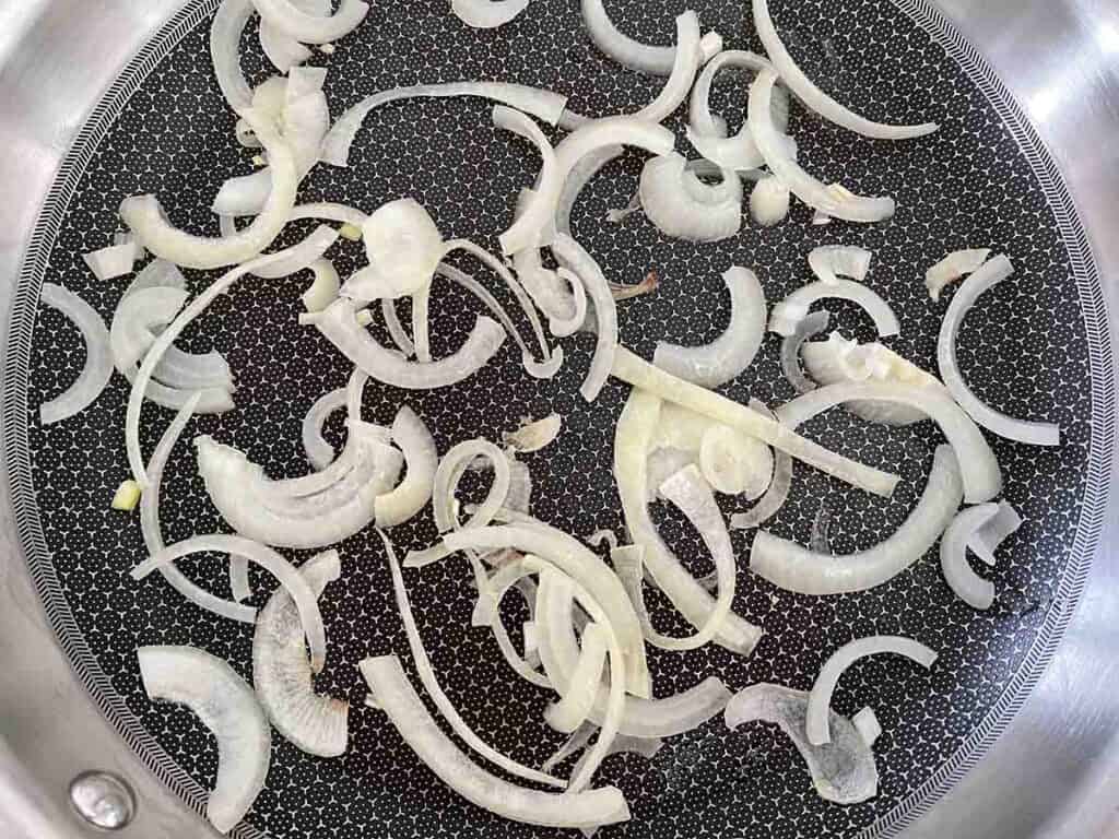 sliced onions frying in a pan.