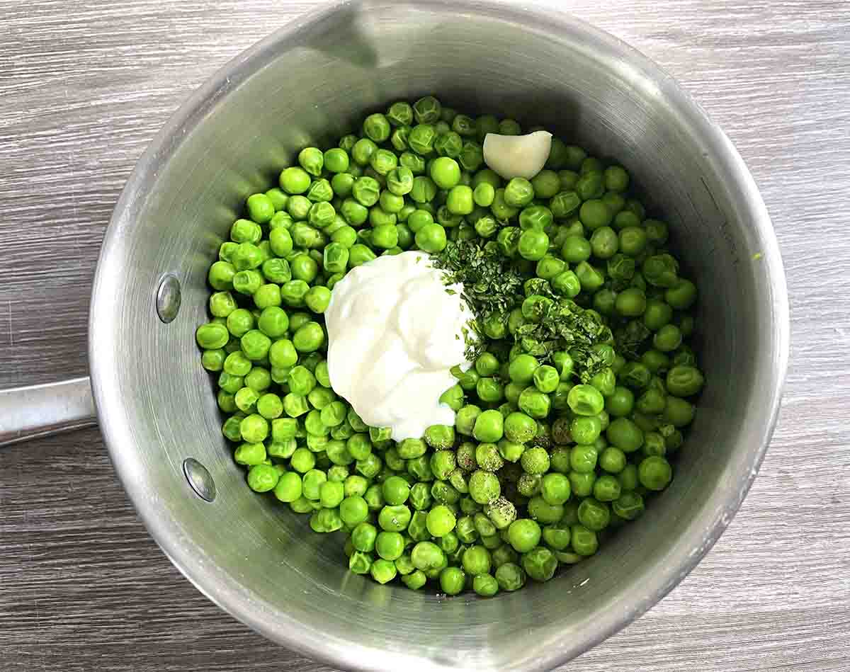 cooked peas in the saucepan with creme fraiche.