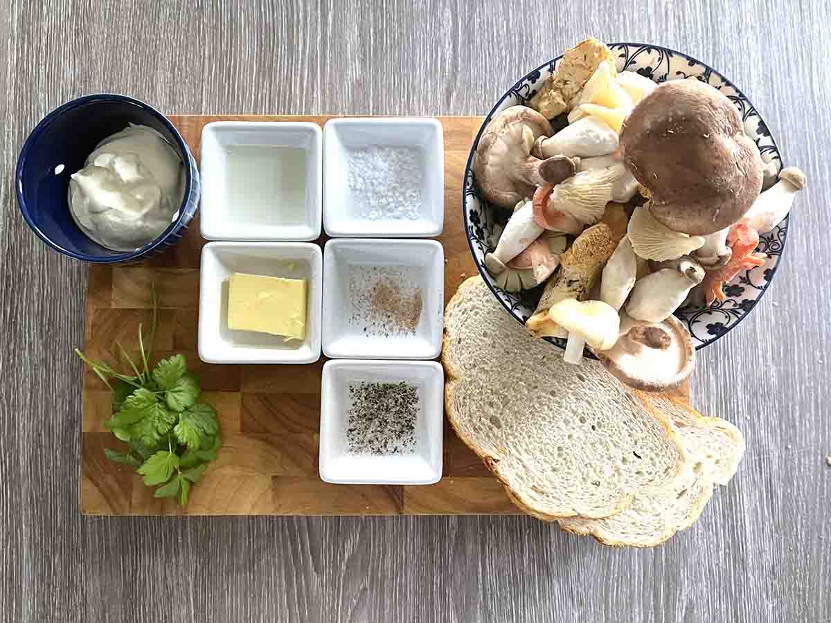 Ingredients in bowlson a board including mushrooms, parsley, bread, butter, oil and cream and seasoning.
