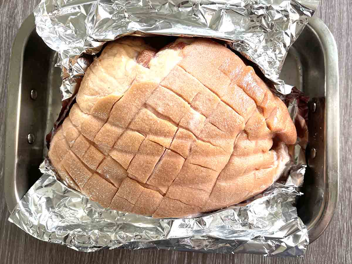 gammon ready for roasting on foil in a dish.
