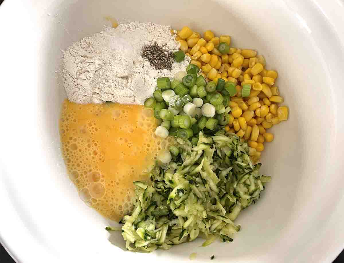 ingredients in a bowl including courgettes, flour and sweetcorn.