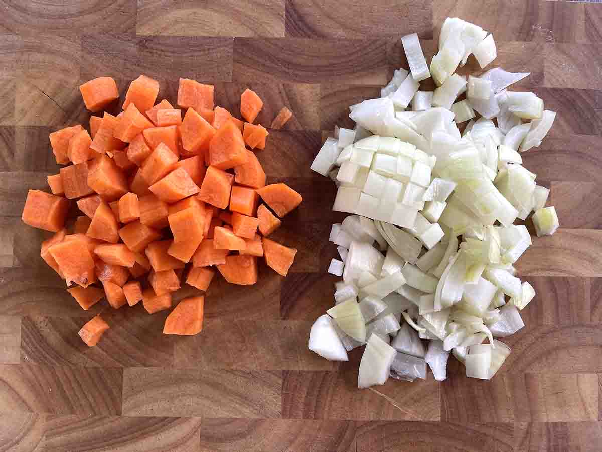 chopped carrots and onions on a board.