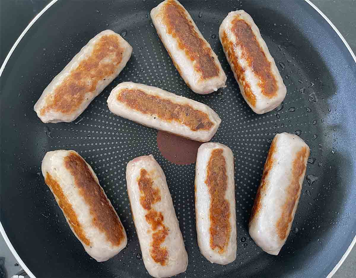 sausages browning in a pan.