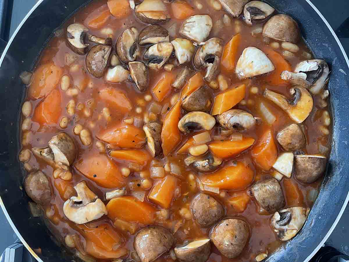 mushrooms, beans, stock and herbs added to pan.