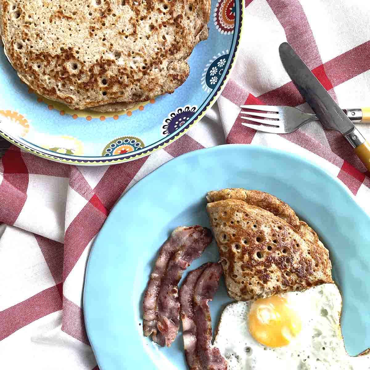Derbyshire oatcake on a plate with egg and bacon.