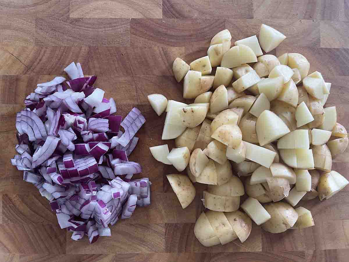 chopped onions and potatoes on a board.
