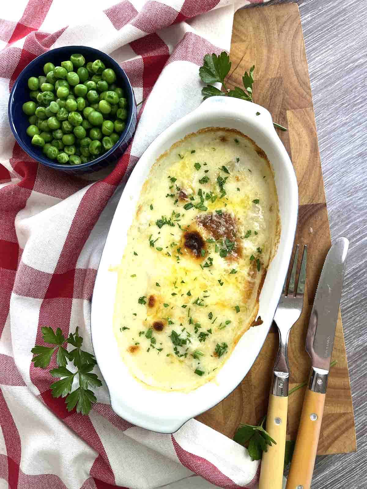 fish bake with peas and cutlery.