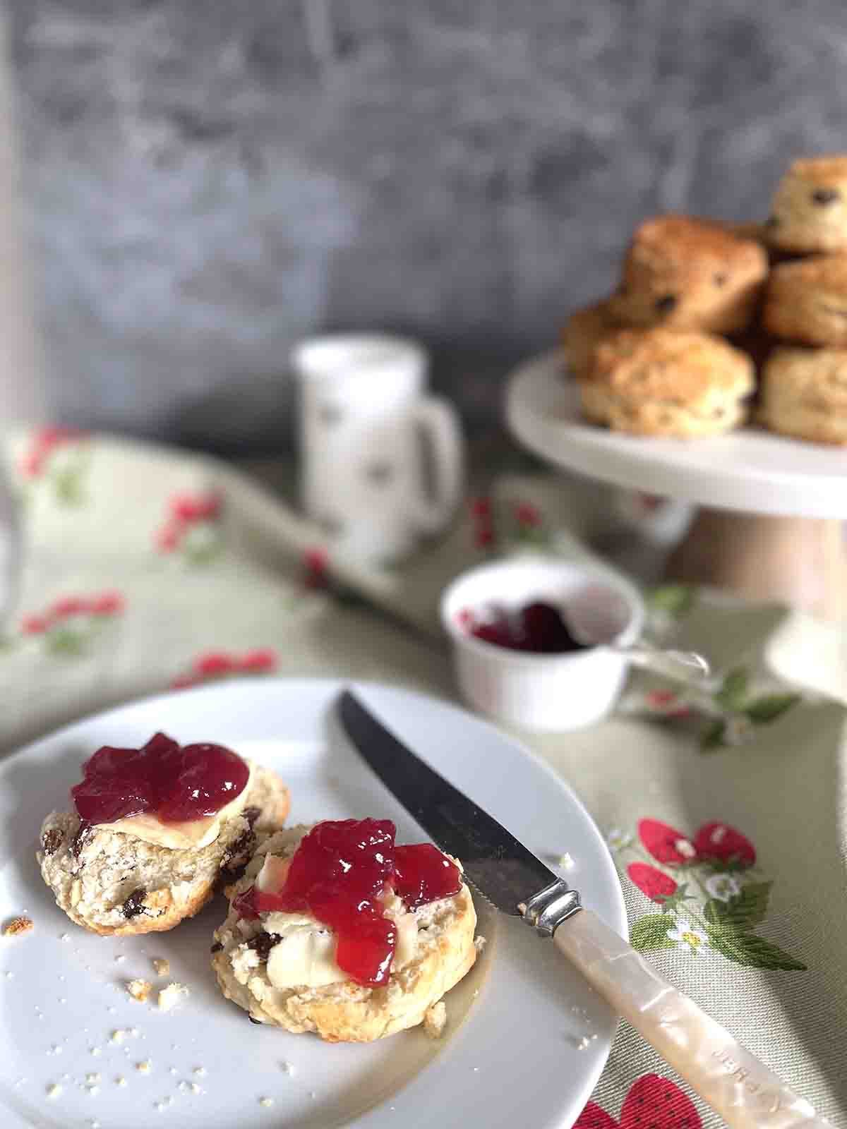 fruit scone with jam on a plate.