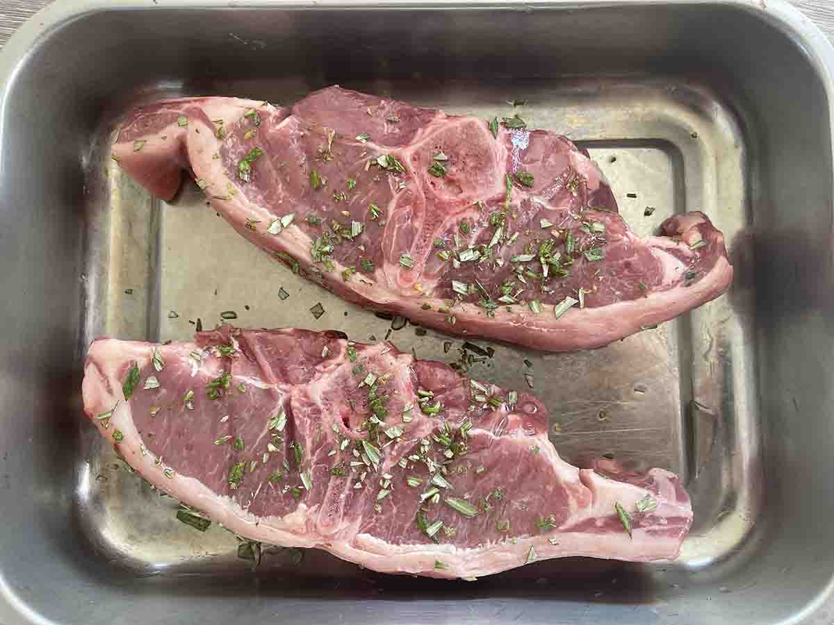 lamb in a dish with oil and rosemary.