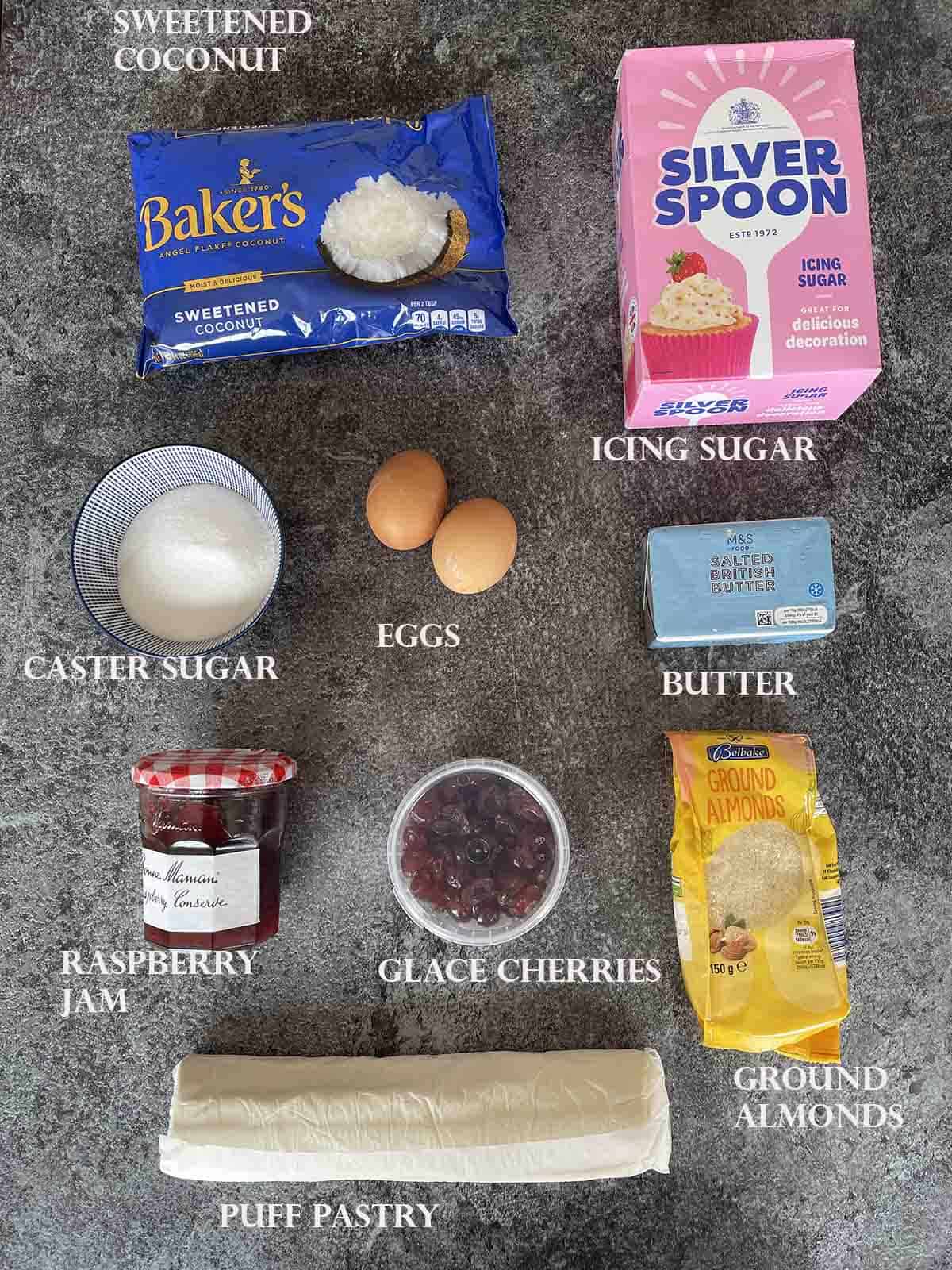 ingredients laid out including jam, pastry, coconut flakes, sugar and almonds.