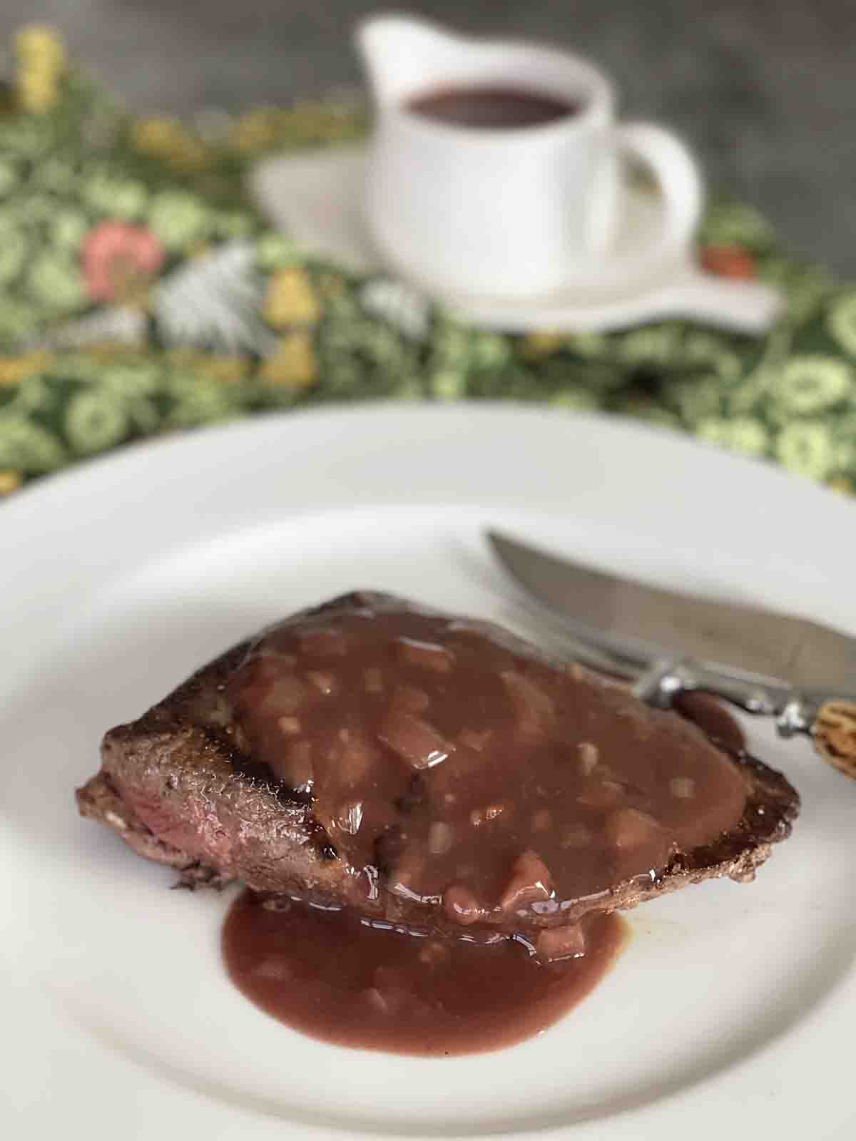 venison haunch steak with sauce poured over.