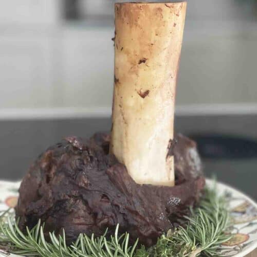 beef shank on a plate with the bone pointing upwards.